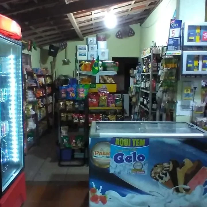 Interior da Conveniência Praieira com geladeiras de bebidas e prateleiras abastecidas